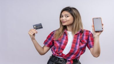 A woman holding up a credit card and her phone.